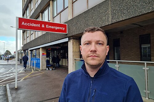 Henry Batchelor in front of NHS sign