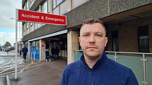 Henry Batchelor in front of NHS sign